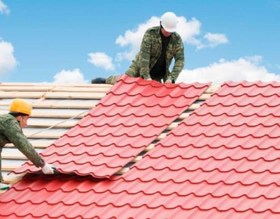 Trabajadores de una obra instalando lámina tipo teja en un techo residencial.